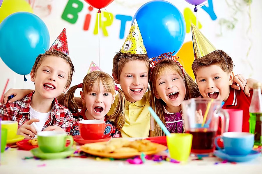Fröhliche Kinder feiern Geburtstag mit Luftballons und Partyhüten